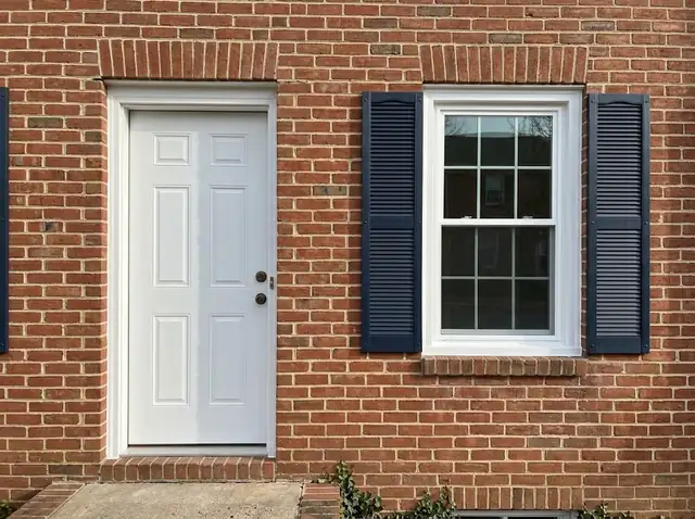 Illustration: new white window with fresh trim in a red brick townhouse wall