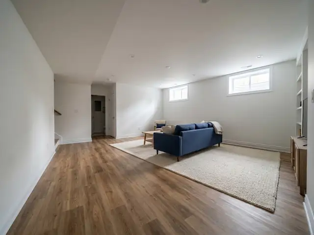 Illustration: finished basement family room with oak-look vinyl plank flooring and white walls