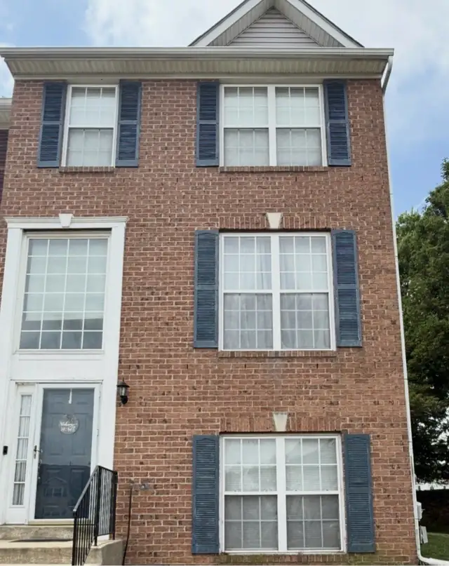 Brick townhouse front with dark blue shutters and white trim windows