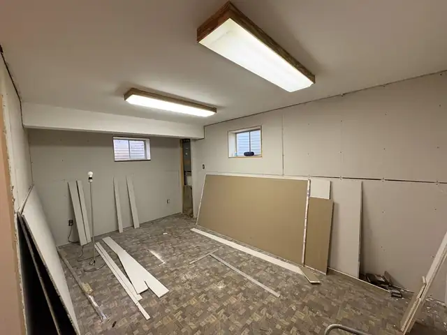 Basement with homeowner-hung drywall before finishing, sheets and tools on the floor