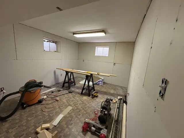 LMG crew's tools, sawhorses and shop vacuum in a basement during drywall taping and mudding